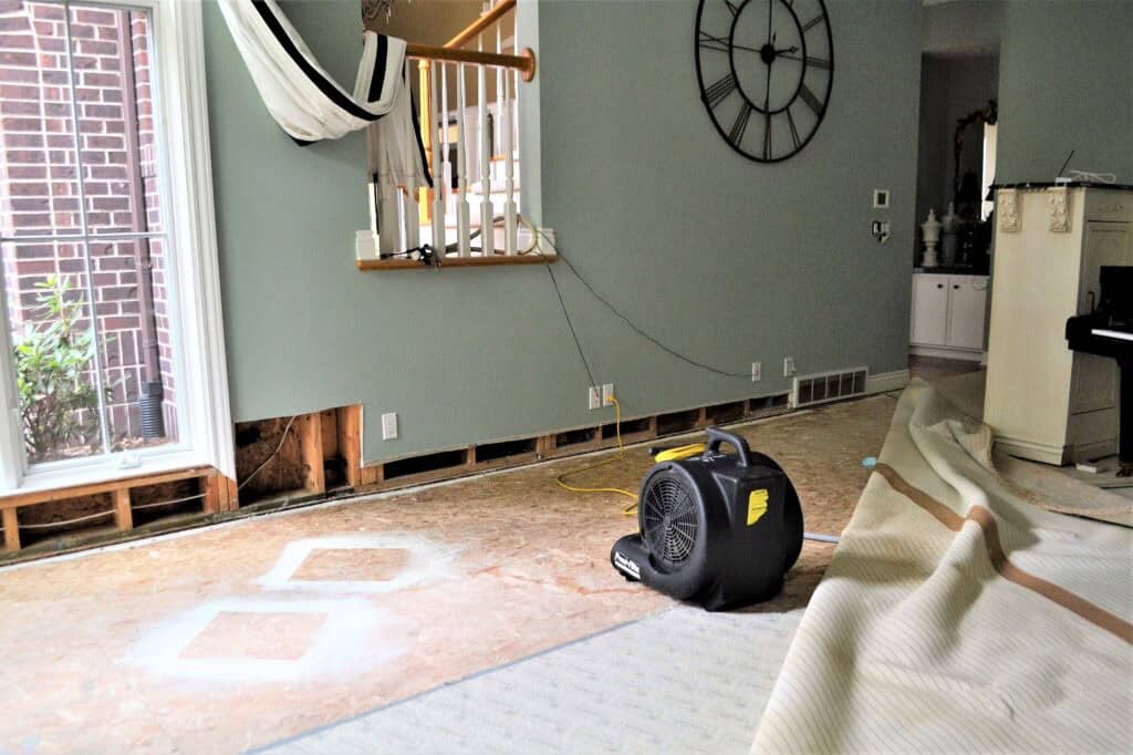 A home restoration contractor installing new drywall as part of a complete water damage repair project, returning the space to pre-loss condition.