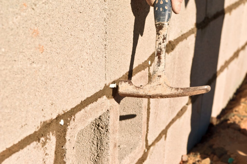 Close-up of a hammer and brick wall for foundation repair in Orange County.